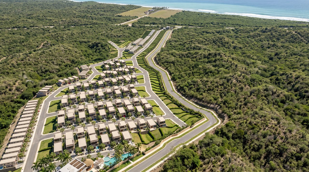 El condominio baja por la ladera hasta la Vía al Mar, con el Caribe al fondo.